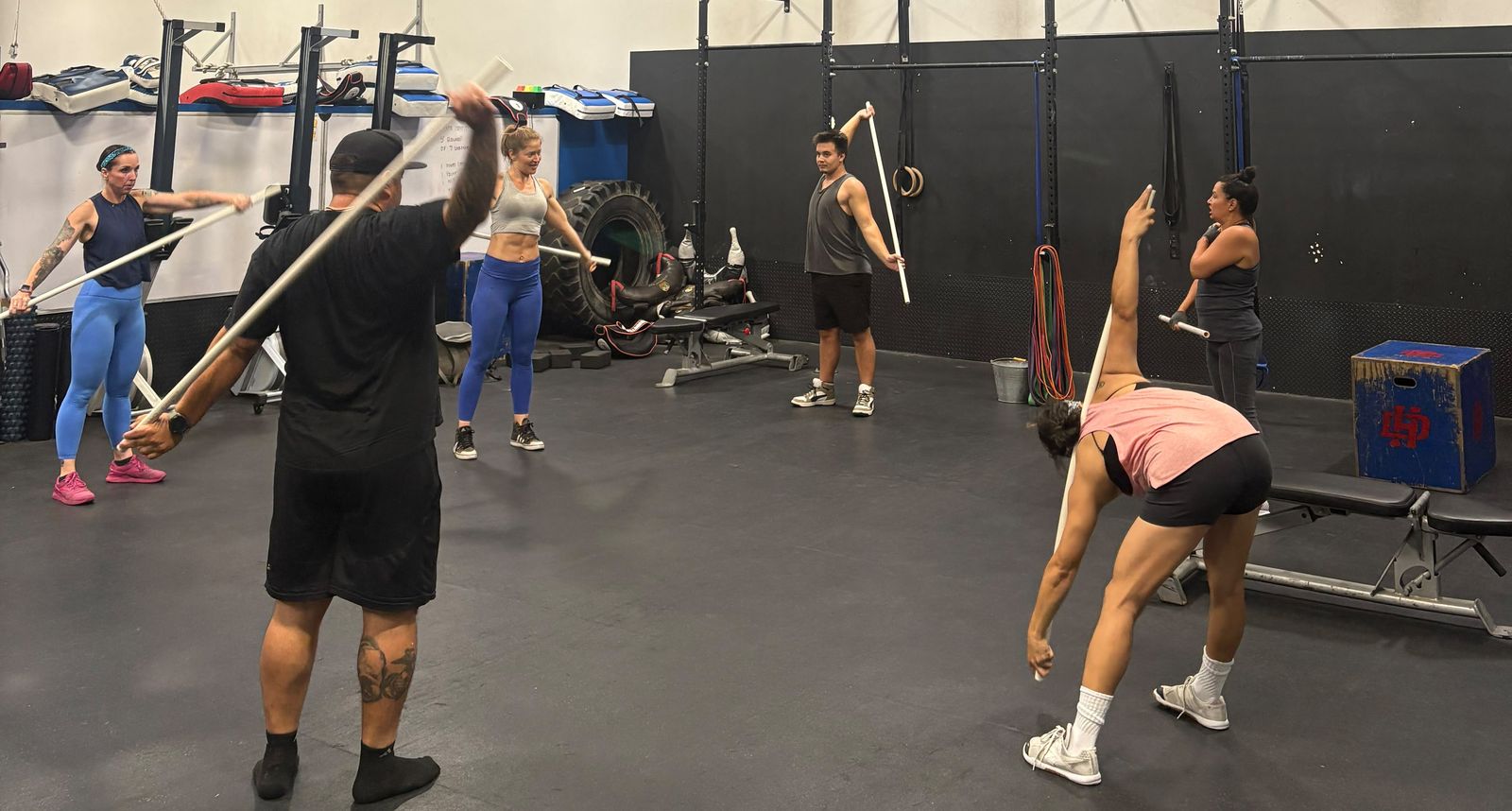 Members training on the weight floor with racks, rings and a tractor tire