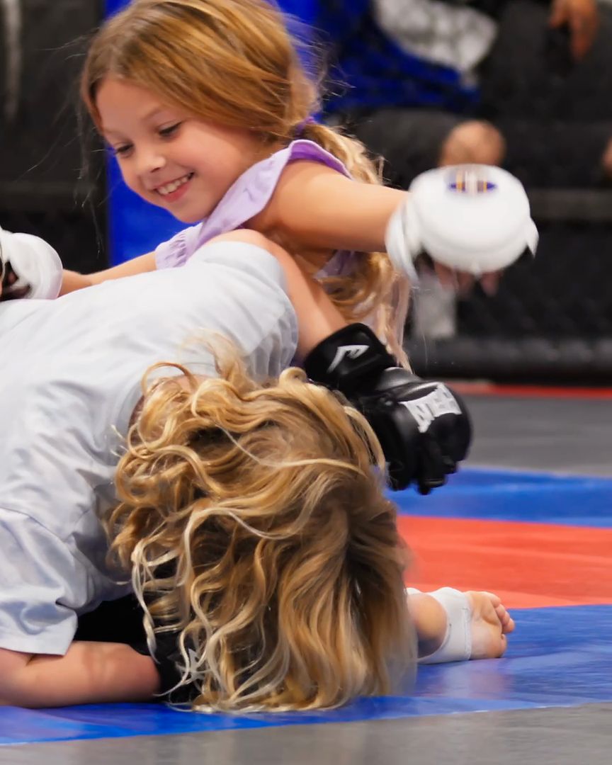 Two young girls grappling and smiling on the mat