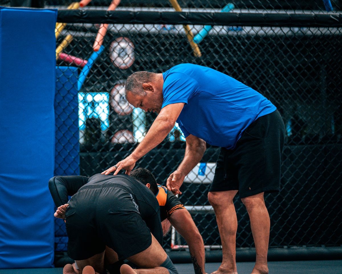 A coach working with two members in the cage