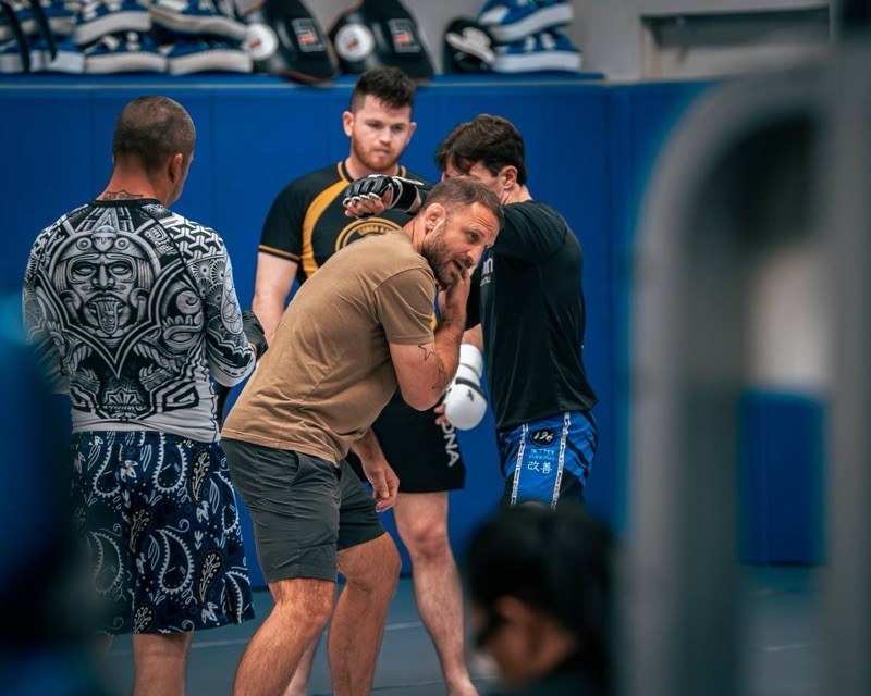 A coach correcting a member's form on the pads